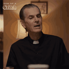 a man in a black shirt with a white collar and the words son of a grifch on the bottom