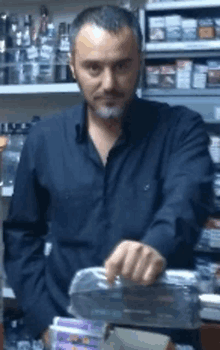 a man in a black shirt is standing in front of a shelf full of alcohol and cigarettes