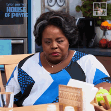 a woman sits at a table in front of a house of payne sign