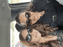 two women wearing sunglasses are in a car