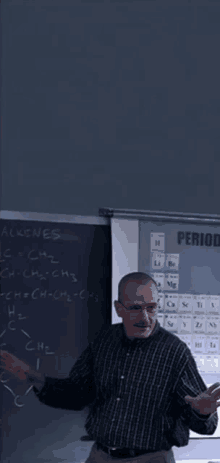 a man stands in front of a chalkboard with the word period on it