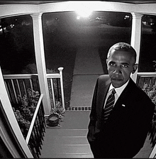 a man in a suit and tie stands on a porch at night