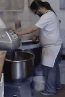 a man in a white shirt and apron is using a mixer