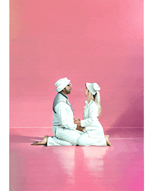 a man and a woman are kneeling on a pink floor holding hands