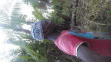 a man wearing a hat and a red shirt is standing in a forest