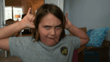 a young girl making a funny face with her tongue sticking out wearing a grey shirt with a patch that says california