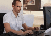 a man in a white shirt is typing on a keyboard in front of a computer with a cup that says chase on it