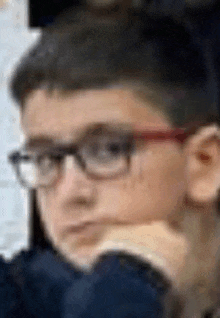 a close up of a young boy wearing glasses and a blue shirt .