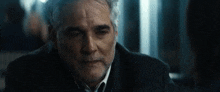 a man with gray hair and a beard is wearing a suit and tie and looking at the camera .