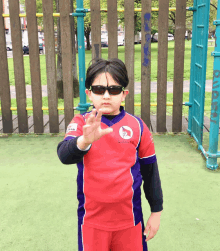 a young boy wearing sunglasses and a red shirt that says ' athletic club ' on the front