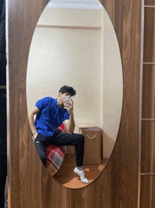 a man in a blue shirt is taking a selfie in front of a mirror