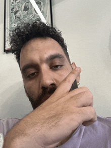 a man with a beard is covering his mouth with his hand in front of a framed poster that says ' the purple '