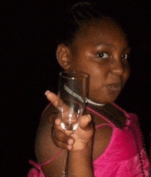 a young girl in a pink dress is holding a glass