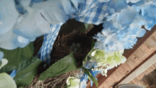 a bird nest surrounded by blue and white flowers and leaves