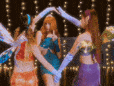 three girls in fairy costumes are standing in a circle with their hands in the air