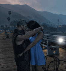 a man and a woman are kissing on a dock