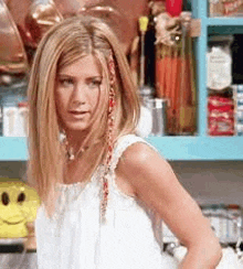 a woman in a white dress is standing in front of a blue shelf in a kitchen .