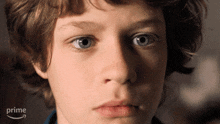 a close up of a young boy 's face with an amazon prime arrow in the background