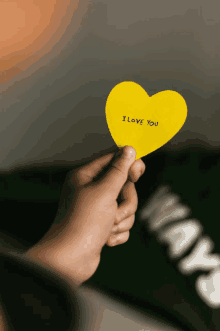 a person is holding a yellow heart that says " i love you "