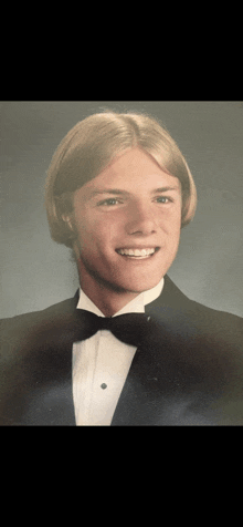 a young man wearing a tuxedo and bow tie smiles