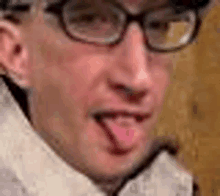 a man with glasses is sticking his tongue out .