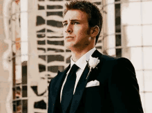 a man in a suit and tie with a white flower in his pocket .