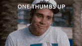 a man wearing a baseball cap and a t-shirt is smiling with the words `` one thumbs up '' above him .