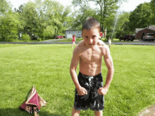 a boy without a shirt is standing in a grassy field