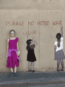 a girl in a purple dress stands in front of a wall that says " please no more war love "