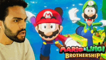 a man with a beard is standing in front of a mario and luigi poster