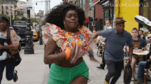 a woman in a colorful top and green shorts is running down a street in front of a store that says harlem ever after