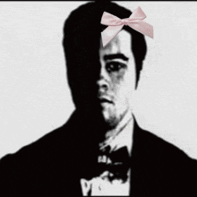 a black and white photo of a man wearing a pink bow tie