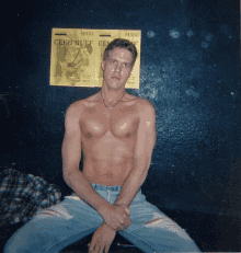 a shirtless man sits in front of a club buff flyer