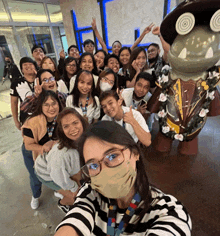 a group of people posing for a selfie with one wearing a mask