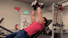 a man in a pink shirt is lifting dumbbells in front of a digital clock that says 22 40 52