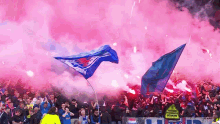 a crowd of people watching a soccer game with smoke coming out of the stands and a sign that says stand