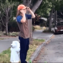 a man standing next to a white fire hydrant talking on his phone