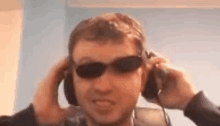 a man wearing sunglasses and headphones is smiling .