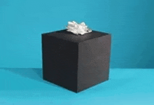 a black box with a white bow is sitting on a blue table .