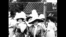 a group of women wearing hats and dresses are standing next to each other in a black and white photo .