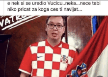 a man in a red and white checkered shirt is standing in front of a flag ..