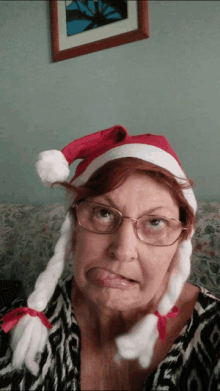 a woman wearing glasses and a santa hat makes a face