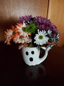 a white ghost shaped vase filled with flowers on a table