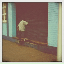 a man riding a skateboard in front of a blue brick building