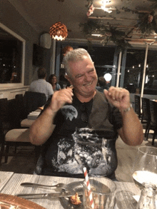 a man wearing a black shirt with a picture of the moon on it sits at a table in a restaurant