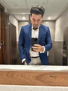 a man in a blue suit is taking a picture of himself in the mirror