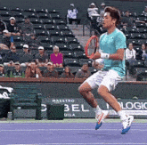 a tennis player is jumping in the air while holding a tennis racquet in front of a sign that says maestro