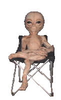 a statue of an alien is sitting on a folding chair