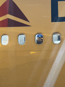 a man in a blue hat looks out the window of a delta airlines airplane