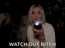 a woman is holding a flashlight in her hand in the dark and says `` watch out bitch '' .